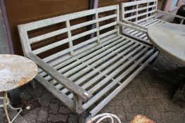 A large hardwood garden settee with loose cushions.