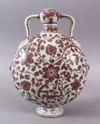 A CHINESE COPPER RED DECORATED PORCELAIN TWIN HANDLE MOON FLASK, decorated with underglaze copper