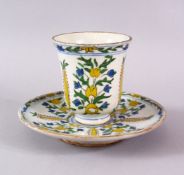 A TURKISH KUTAHYA POTTERY CUP & SAUCER, decorated with bands of floral motif with yellows, blue