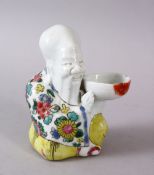 A CHINESE FAMILLE JAUNE / ROSE PORCELAIN FIGURE OF SHOU LAO, in a seated position holding a bowl,