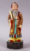 A 19TH / 20TH CENTURY CHINESE FAMILLE ROSE PORCELAIN FIGURE OF AN IMMORTAL, stood upon a wood