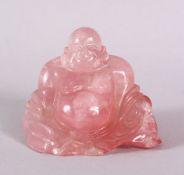 A CHINESE CARVED ROSE QUARTS FIGURE OF BUDDHA, in a reclined position with the usual humorous