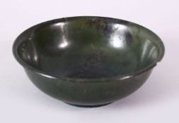 A PLAIN CHINESE CIRCULAR JADE BOWL, with mottled decoration, signed on base, 12cm diameter.