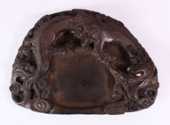A 19TH CENTURY CHINESE SHAPED INKSTONE, carved with dragons, 23cm x 17cm.