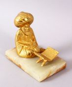 A TURKISH GILT BRONZE FIGURE OF A SEATED FIGURE, seated with a quran stand, mounted to a stone base,