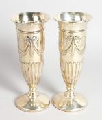 A PAIR OF SILVER FLUTED FLOWER VASES on circular bases 9 ins high,