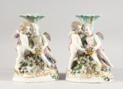 A PAIR OF 19TH CENTURY MEISSEN STYLE PORCELAIN CANDLESTICK GROUP of cupids holding baskets Cross