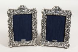 A PAIR OF REPOUSSE DECORATED PHOTOGRAPH FRAMES 7 ins x 5 ins.