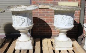 A SUPERB NEAR PAIR OF ITALIAN CARVED WHITE MARBLE URNS ON STANDS, the sides covered with dancing