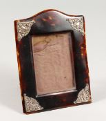 A SILVER MOUNTED UPRIGHT TORTOISESHELL PHOTOGRAPH FRAME with serpentine top , leather back, 6 ins