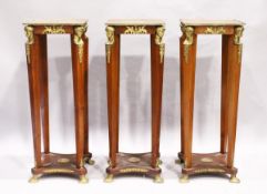 A SET OF THREE SQUARE TOP TORCHERES with mask mounts, tapering supports, undertier and gilt legs.