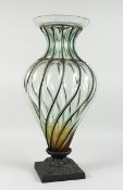 A LARGE GLASS VASE with metal mounts on a square base, 2 ft. 2 in. high.
