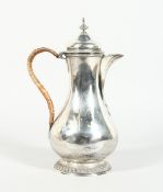 A GEORGE III SILVER PEAR SHAPED COFFEE POT and cover with a raffia handle and armorial crest, 10.5