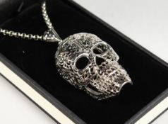 A SILVER SKULL PENDANT on a chain.