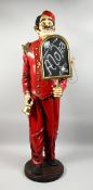 A COMPOSITION DOORMAN with a placard and bell, 5 ft high.