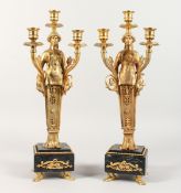 A GOOD PAIR OF EMPIRE DESIGN CLASSICAL THREE LIGHT CANDLESTICKS on marble bases. 18 ins high.