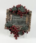 A SMALL MIRROR with fruiting vines in a composition frame, 14 in. x 10 in.