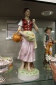 A large Royal Dux figure of a young lady gathering fruit in her apron.