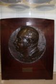 A French bronze circular relief carved plaque of a gentleman mounted on a mahogany frame.