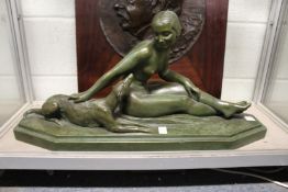 A good large green bronze patinated pottery Art Deco group of a seated female nude with a dog by her
