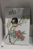 A Chinese porcelain panel depicting a bird on a branch.