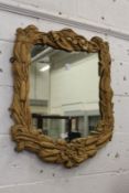 A wall mirror with a decoratively carved hardwood frame.