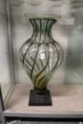 A large moulded glass and wrought iron pedestal vase.