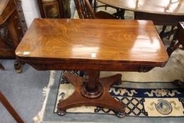 A 19th century mahogany foldover card table on an octagonal column with platform base and bun feet.