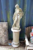 A garden figure of a classical female on a column support.