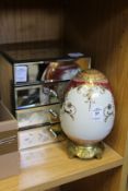 A porcelain egg and a mirrored jewellery chest.