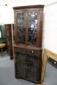 A large mahogany standing corner display cabinet.