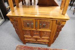 A Chinese altar cabinet with carved decoration and various drawers and cupboard doors.