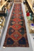 A Persian runner, dark red and blue ground with large diamond shaped motifs.