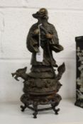 A Chinese bronze standing Buddha on a hardwood stand.