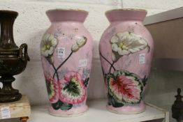 A pair of floral painted pink vases.