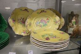 Seven yellow ground plates painted with flowers, with three matching serving dishes.
