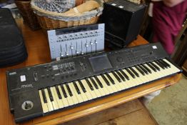 A Korg electronic keyboard together with a Roland cube monitor and a mixer.