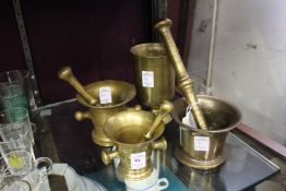 Three brass pestles and mortars and a similar beaker.