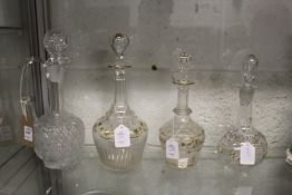 A cut glass claret jug and three decanters with gilded and floral decoration.