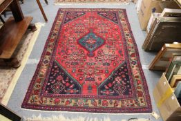 A Persian rug, red ground with stylized decoration.