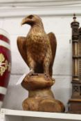 A carved wood model of an eagle on a rock.