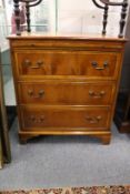 A reproduction yew wood three drawer chest with brushing slide.