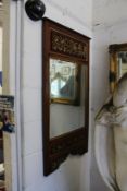 A decorative hardwood framed mirror with carved and painted panels.