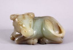 A CHINESE CARVED JADE FIGURE OF A RECUMBENT COW / OX, in a recumbent pose bearing a grin, 12cm