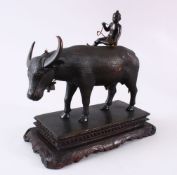 AN IDIAN JAIPUR SCHOOL BRONZE MODEL OF A COW, with a boy seated upon its back, mounted to a carved