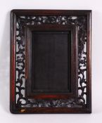 A CHINESE CARVED HARDWOOD FRAME, carved with openwork of flora, 26cm x 20cm.`