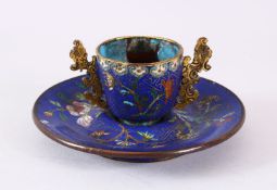 A CHINESE CLOISONNE TEA CUP AND SAUCER, upon a blue ground with lotus decoration, 6cm high x 13cm