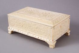 A 19TH CENTURY INDIAN MUGHAL CARVED IVORY LIDDED BOX, carved with roundel of foliage, on four carved