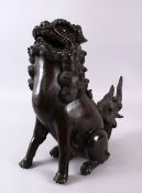 A 19TH CENTURY CHINESE BRONZE LION DOG CENSER, in a seated pose, the cover to its back, 38cm high.