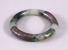 A CHINESE CARVED MOSS GREEN & WHITIE METAL BANGLE, the jade a translucent white with moss green